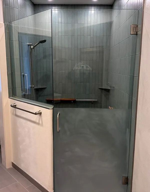 Glass shower enclosure with vertical stacked teal tile